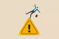 businessman tripping on caution sign to illustrate a mistake